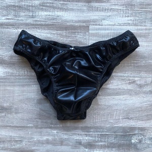 May include: Black shiny underwear with a smooth, sleek fabric. The underwear has a low rise and a classic cut.