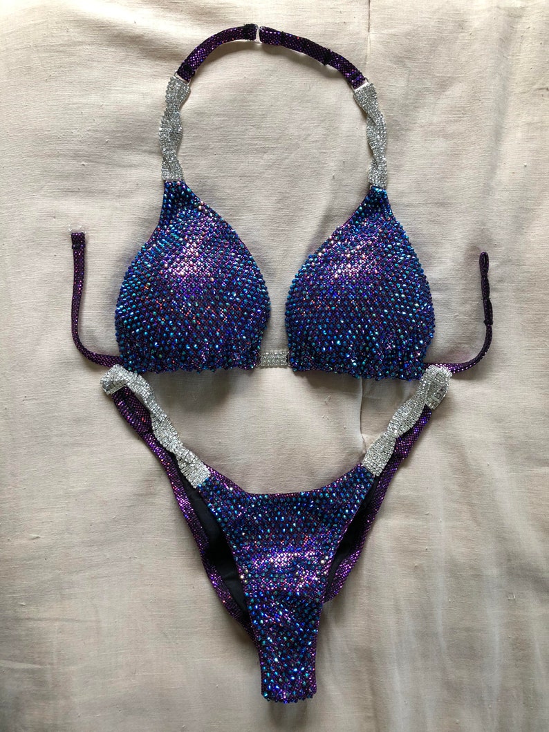 Może przedstawiać: Fioletowy i srebrny cekinowy bikini z gorsetem halter i wysokimi wycięciami.
