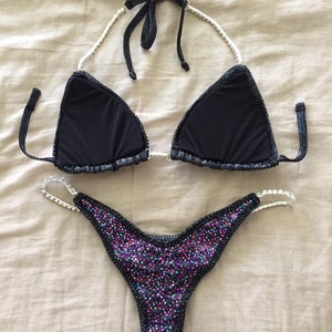 May include: Black bikini with a crystal-embellished top and a bottom with iridescent crystals.