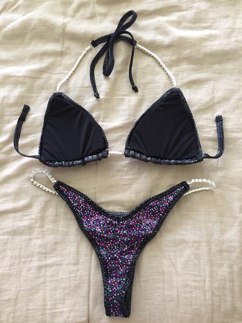 May include: Black bikini with a crystal-embellished top and a bottom with iridescent crystals.