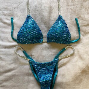 May include: A turquoise and silver sequined bikini with a triangle top and a high-cut bottom.