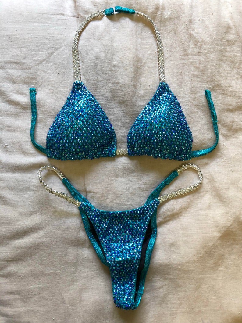 May include: A turquoise and silver sequined bikini with a triangle top and a high-cut bottom.