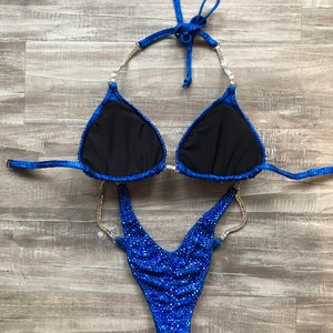 May include: A blue and silver sequined competition bikini with a V-shaped bottom and a halter top.