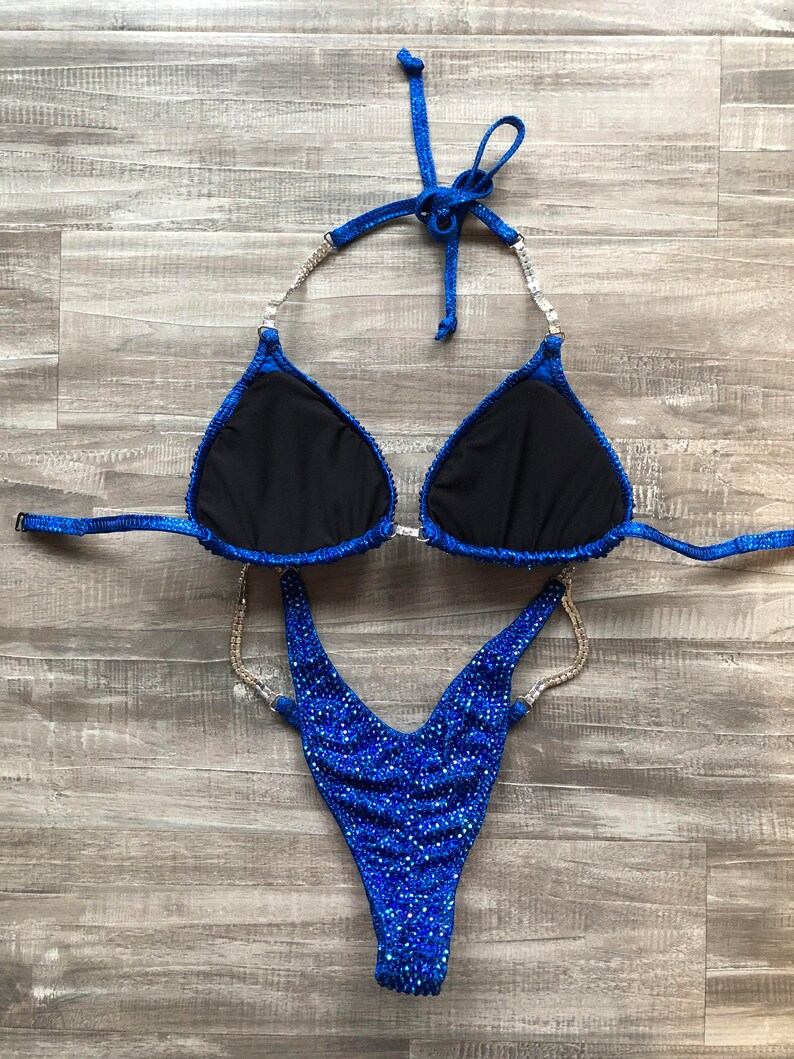 May include: A blue and silver sequined competition bikini with a V-shaped bottom and a halter top.