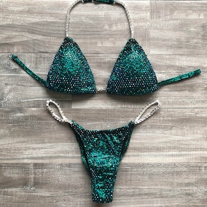 May include: A green and silver sequined bikini with a halter top and a high-cut bottom.