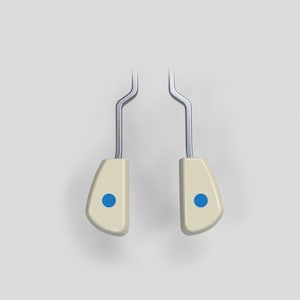 May include: A pair of cream-coloured shoe stretchers, each with a blue dot and a silver metal handle. These are designed to widen and lengthen shoes. The background is plain white.