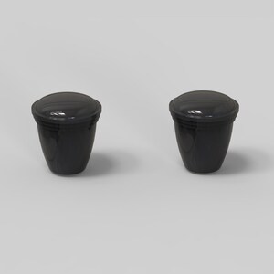 Puede incluir: Dos recipientes de pl&aacute;stico negro con tapas. Los recipientes son redondos y tienen un acabado liso y brillante.