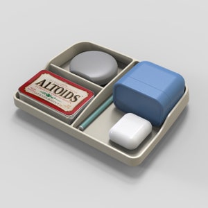 May include: A beige tray with compartments holds a pack of Altoids peppermint mints, a blue rectangular container, a white round object, and a white rectangular object.