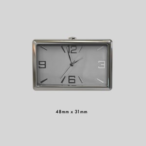May include: A silver rectangular clock with black Roman numeral markings on a white face. The clock measures 48mm x 31mm.