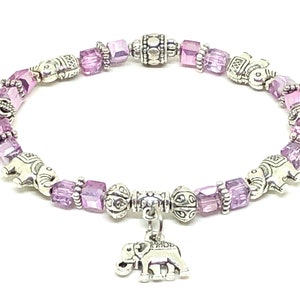 May include: A silver charm bracelet with purple crystal beads and silver elephant charms. The bracelet has a dangling elephant charm.