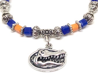 May include: A silver charm bracelet with blue and orange beads and a silver alligator charm.