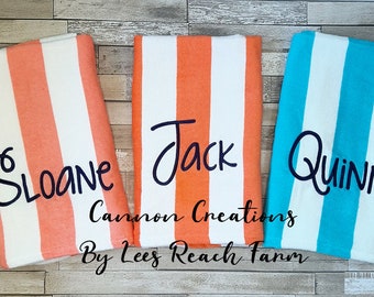 May include: Three personalized beach towels with vertical stripes in coral, orange, and turquoise, each with a name in cursive: Sloane, Jack, and Quinn. The towels are labeled "Cannon Creations By Lees Reach Farm."