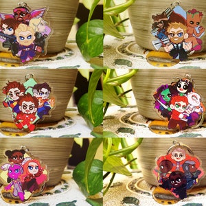 May include: Set of six colorful cartoon character keychains featuring characters from popular superhero movies. Each keychain is made of clear acrylic and features a different group of characters.