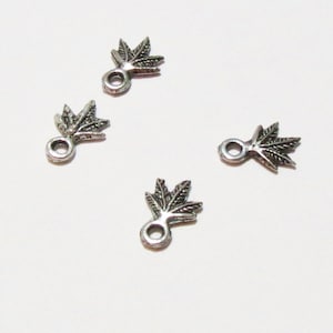May include: Four silver-toned leaf-shaped charms with a loop at the top. Each charm features a detailed leaf design.
