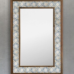 May include: Rectangular mirror with a wooden frame and a decorative border of small, square tiles. The tiles feature a blue and white geometric pattern. The mirror is designed for wall mounting and adds a decorative touch to any room.