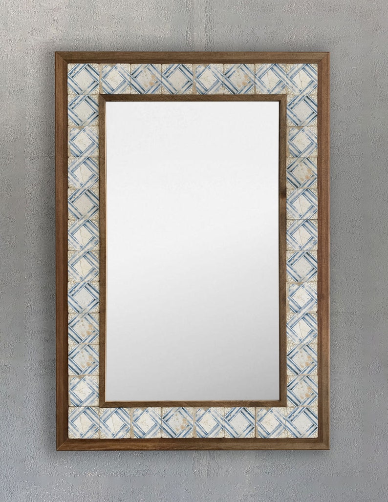 May include: Rectangular mirror with a wooden frame and a decorative border of small, square tiles. The tiles feature a blue and white geometric pattern. The mirror is designed for wall mounting and adds a decorative touch to any room.
