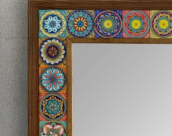 May include: A rectangular mirror with a wooden frame. The frame is adorned with colorful, square tiles featuring intricate floral and geometric patterns in shades of blue, yellow, red, and green. The mirror reflects a neutral gray background.
