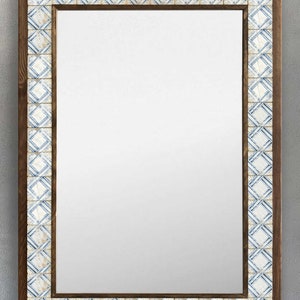 May include: Rectangular mirror with a dark brown wooden frame. The frame is accented with a border of square tiles in white and blue geometric patterns. The mirror's reflective surface is clear.