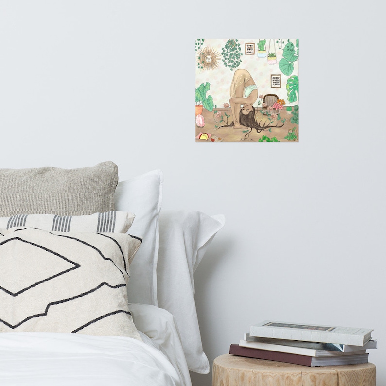 Puede incluir: Una impresi&oacute;n que presenta a una persona en una postura de yoga con un le&oacute;n. La ilustraci&oacute;n tiene una paleta de colores neutros con plantas verdes y el texto "Good Vibes Only". La obra de arte se muestra en una pared blanca, con almohadas y una mesa auxiliar en primer plano.