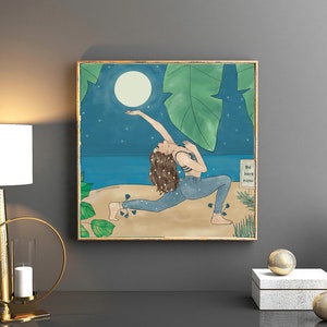 May include: Square framed art print depicting a person in a yoga pose reaching for a full moon. The artwork features a beach scene with a dark blue sky, stars, and large green leaves. The text "Be here now" is visible.