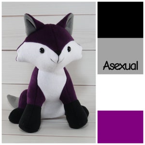 May include: Purple plush fox with black paws and a white belly. The fox is sitting on a white wooden surface. The image also includes a color swatch of black, gray, and purple, with the word "Asexual" in black text on a gray background.