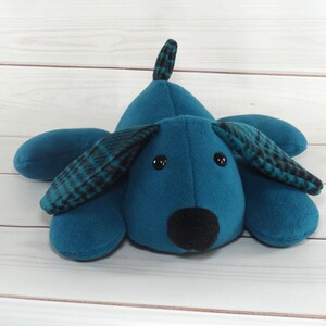 May include: A teal blue plush dog toy with black eyes and a black nose. The dog has black and teal plaid ears.