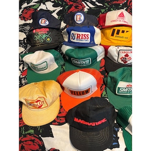 以下が含まれることがあります： Roadway、Citgo、Kendall Racing、Riss International、Plymouth Rock、Smith's、Old Dominion、Yellow、Magnatudeなどの企業ロゴやブランド名が入った、様々な色のヴィンテージトラッカーキャップ12個セット。