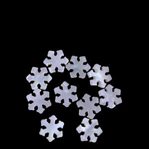 May include: A collection of iridescent white snowflake-shaped embellishments against a black background. Each snowflake has six points and a pearlescent sheen. These decorative pieces are ideal for craft projects or holiday decorations.