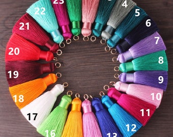 May include: A set of 23 colorful tassels with gold rings. The tassels are arranged in a circle, with the numbers 1 through 23 printed on each tassel.