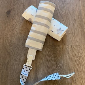 May include: A white and gray striped fabric baby teether with a white plastic clip and a white and black patterned strap with the text "Pura & Co.".