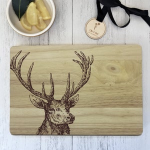 Può includere: Un tagliere in legno con un design a testa di cervo marrone. Il tagliere è in legno chiaro e ha una finitura naturale.