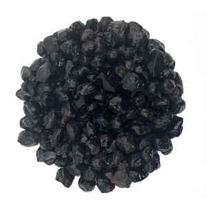 May include: A close-up of a pile of black obsidian stones. The stones are smooth and shiny, and they have a dark, almost black color.