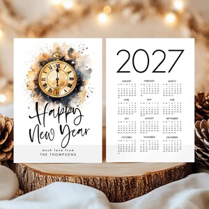 May include: A 2027 calendar card featuring a watercolour pocket watch illustration, the text Happy New Year, and the personalised line much love from THE THOMPSONS. The reverse side displays the full 2027 monthly calendar grid in black text.