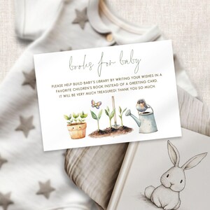 May include: A white card with the text "books for baby" and a request to write wishes in a children's book. The card features watercolor illustrations of a potted plant, seedlings, a butterfly, and a watering can.