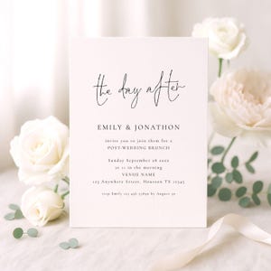 Może przedstawiać: Kremowa karta zaproszenia z napisem "the day after" w eleganckiej czcionce. Karta zaprasza gości na brunch po weselu, podając datę, godzinę i miejsce. Białe róże i zieleń otaczają kartę, z białą wstążką na pierwszym planie.