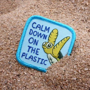 Puede incluir: Un parche azul y blanco con una tortuga de mar de dibujos animados y el texto "Calm Down On The Plastic".