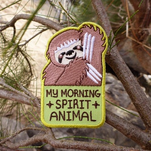 May include: A green and brown embroidered patch featuring a cartoon sloth and the text "MY MORNING SPIRIT ANIMAL".