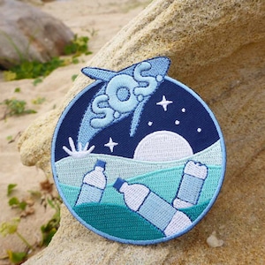 Könnte beinhalten: Gestickter Aufnäher mit einer blauen und weißen SOS-Botschaft in einer stilisierten Schrift, einem weißen Mond und Sternen vor einem dunkelblauen Hintergrund. Zwei weiße Plastikflaschen sind teilweise in einem türkisfarbenen Meer versunken.