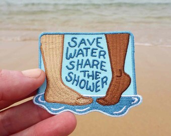 May include: A blue and white embroidered patch with two feet stepping into water. The text reads "Save Water Share the Shower".