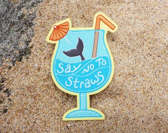 Può includere: Una toppa ricamata blu e gialla con un bicchiere da cocktail, una cannuccia, un ombrello e una coda di balena. Il testo "Say no to straws" è ricamato sul bicchiere.