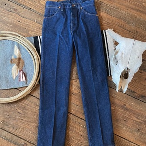 May include: A pair of dark blue denim jeans with a straight leg fit. The jeans have a classic five-pocket design and a button fly.