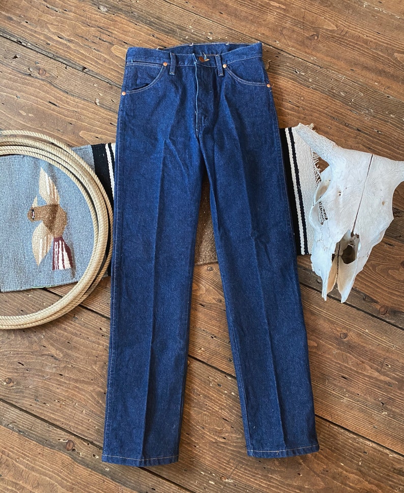 May include: A pair of dark blue denim jeans with a straight leg fit. The jeans have a classic five-pocket design and a button fly.