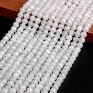 May include: A strand of white moonstone beads. The beads are round and smooth, with a subtle iridescent sheen.