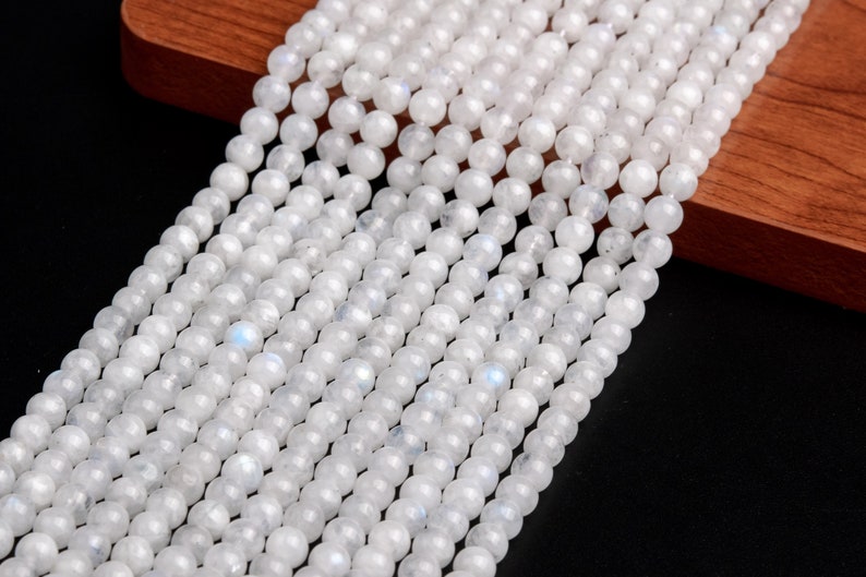 May include: A strand of white moonstone beads. The beads are round and smooth, with a subtle iridescent sheen.