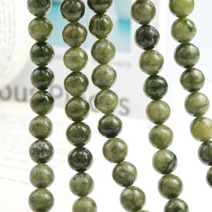 Pu&ograve; includere: Una collana di perle di pietre preziose verdi, ogni perla &egrave; rotonda e presenta un motivo screziato. Le perle sono infilate su un filo trasparente e sono disposte in una linea verticale.