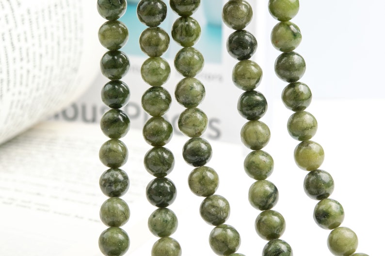 Pu&ograve; includere: Una collana di perle di pietre preziose verdi, ogni perla &egrave; rotonda e presenta un motivo screziato. Le perle sono infilate su un filo trasparente e sono disposte in una linea verticale.