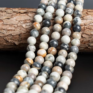 May include: A strand of round, gray, white, and brown agate beads. The beads are smooth and polished, and they have a natural, organic look.