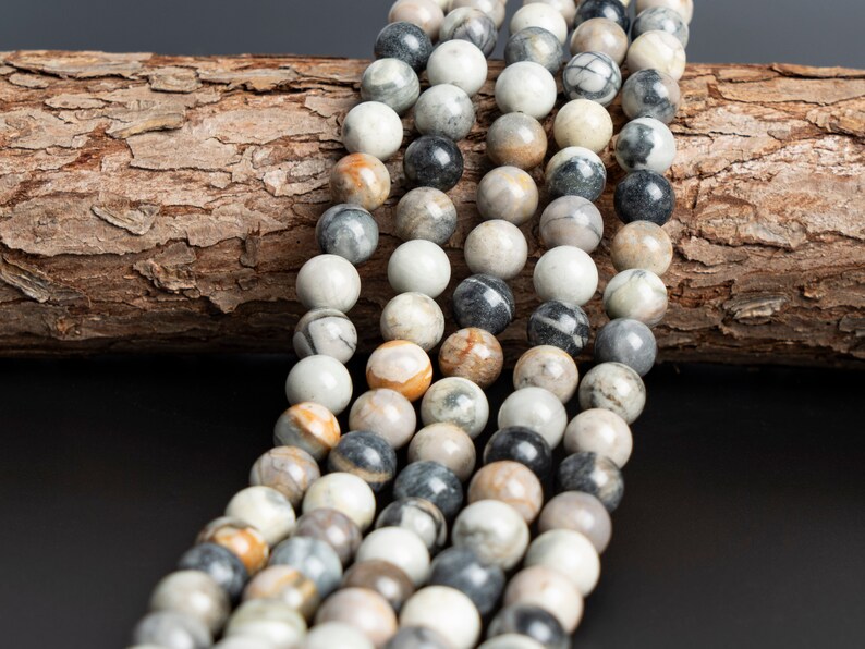 May include: A strand of round, gray, white, and brown agate beads. The beads are smooth and polished, and they have a natural, organic look.