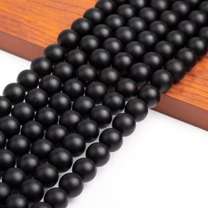 May include: A strand of black matte round beads. The beads are smooth and have a slightly textured surface.