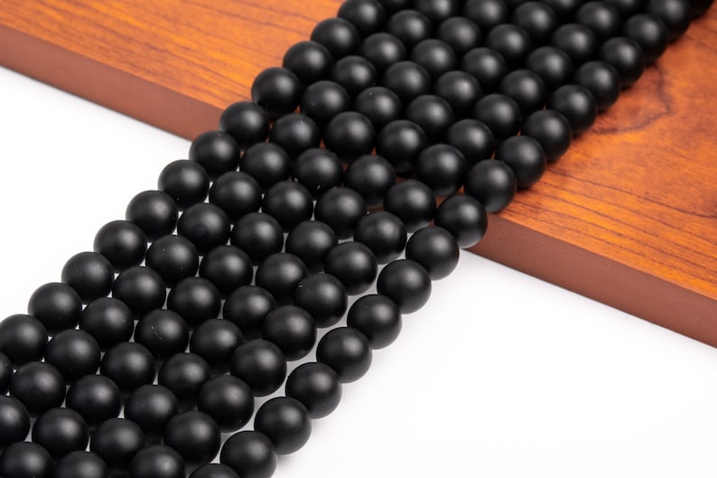 May include: A strand of black matte round beads. The beads are smooth and have a slightly textured surface.